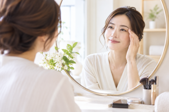 鏡で眉の仕上がりを確認する女性のイメージ