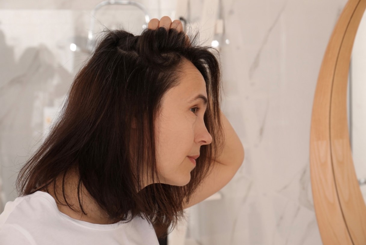 鏡を見ながら髪や頭皮の状態を確認する女性
